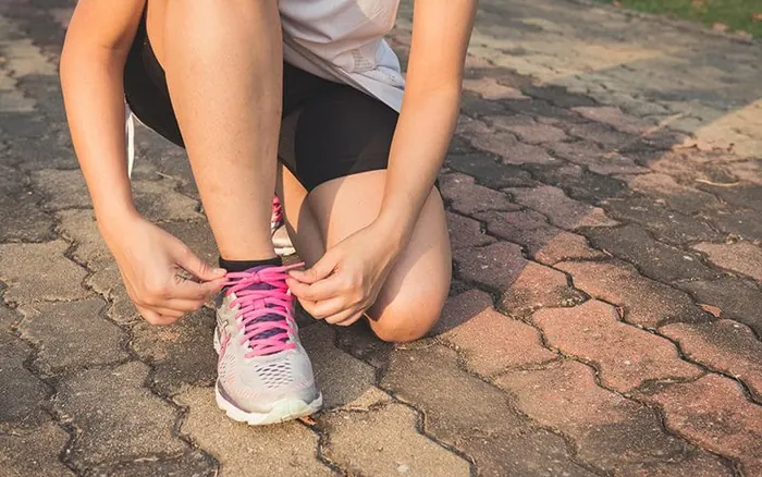 person on one knee tying shoe