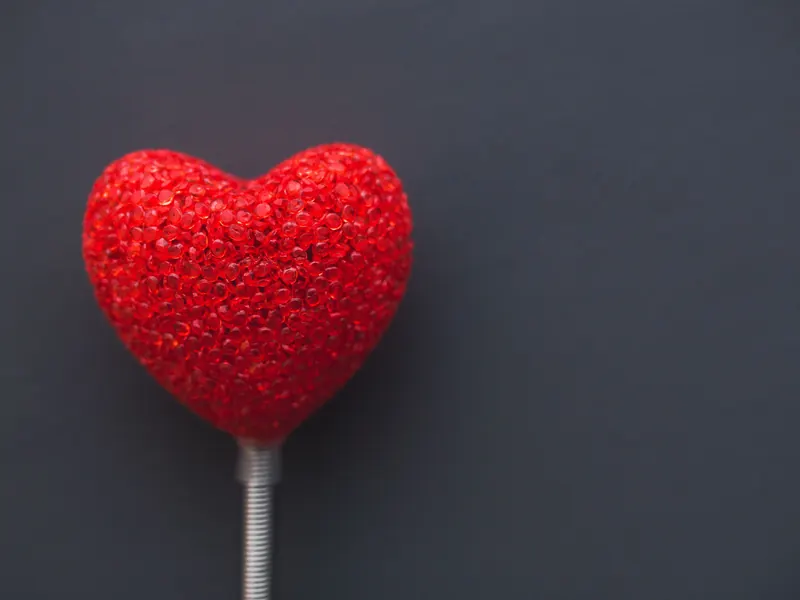 red heart on a white stick against dark gray background