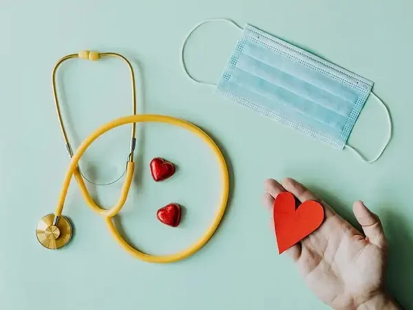 stethoscope, hand holding a heart, and a mask