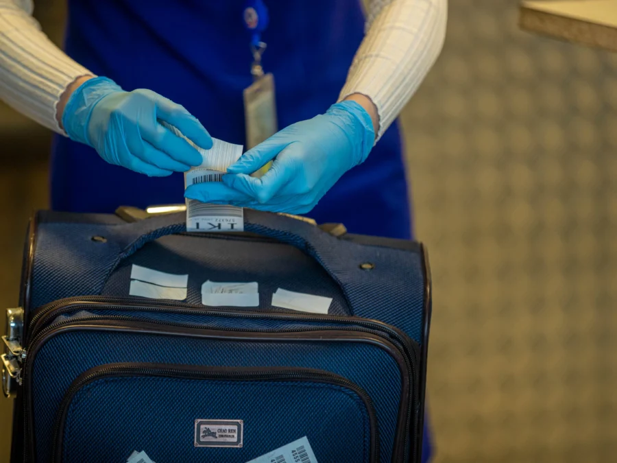 airport employee putting a tag on a suitcase
